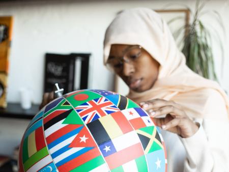 A Women holding a globe, coloured in all the international flags 