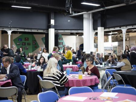 Photo of people around tables at ACH event