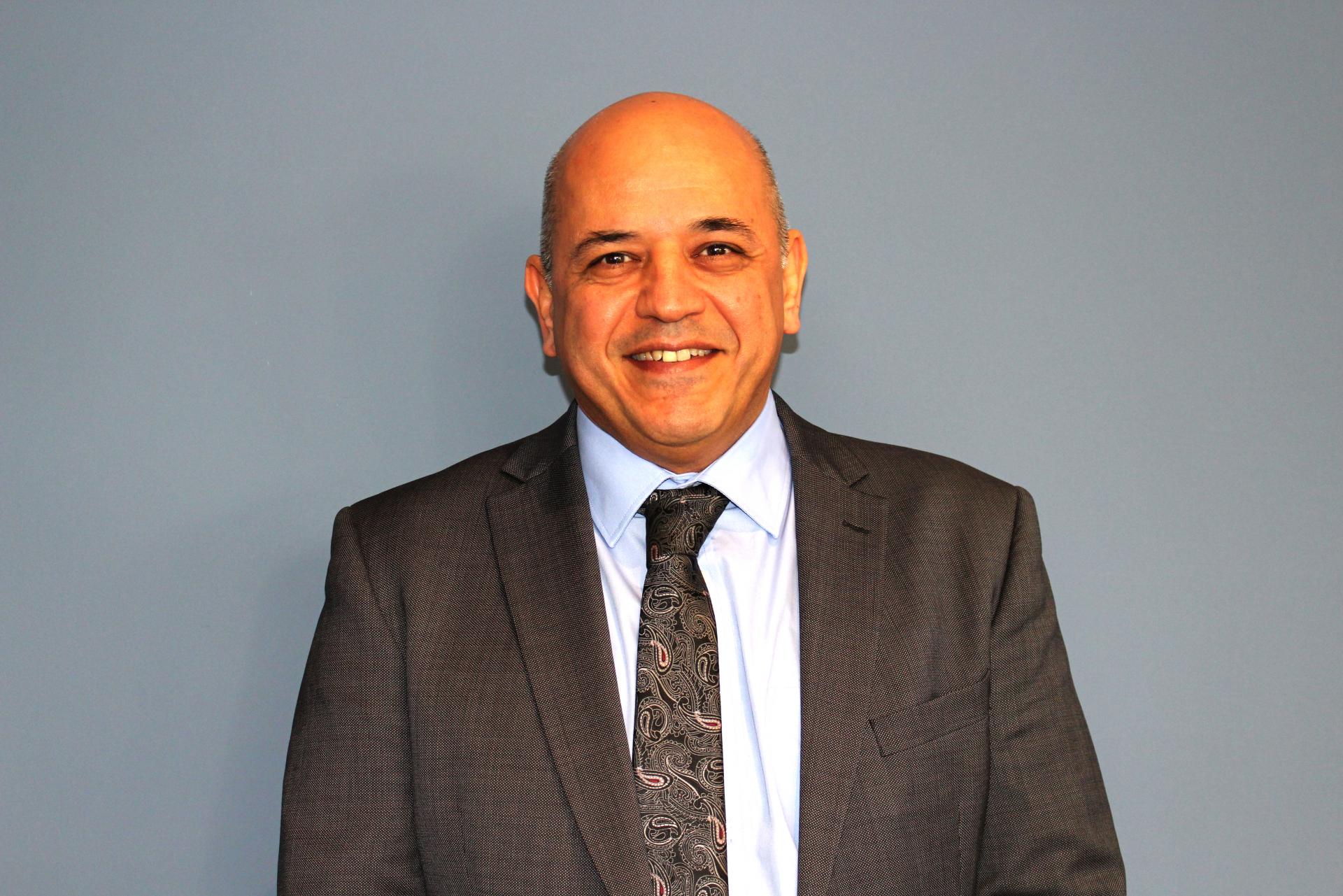 Headshot of R Shariat for a meet the board post for ACH migrant and refugee charity