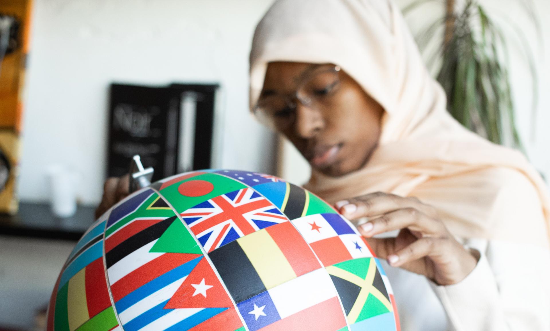 A Women holding a globe, coloured in all the international flags