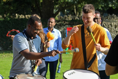 Two ACH staff members playing drums at staff away day